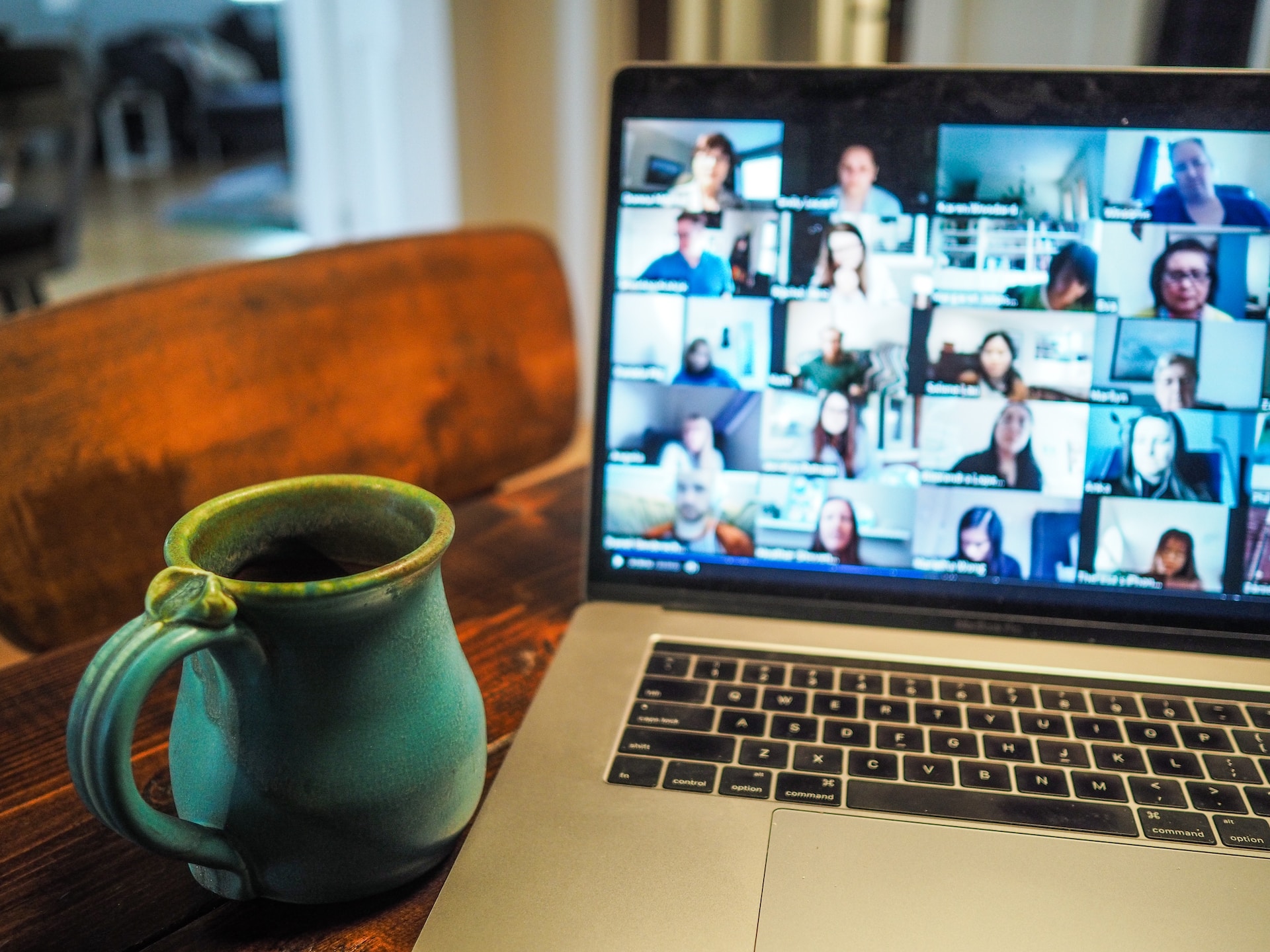 Zoom meeting on MacBook with blue mug on table. 